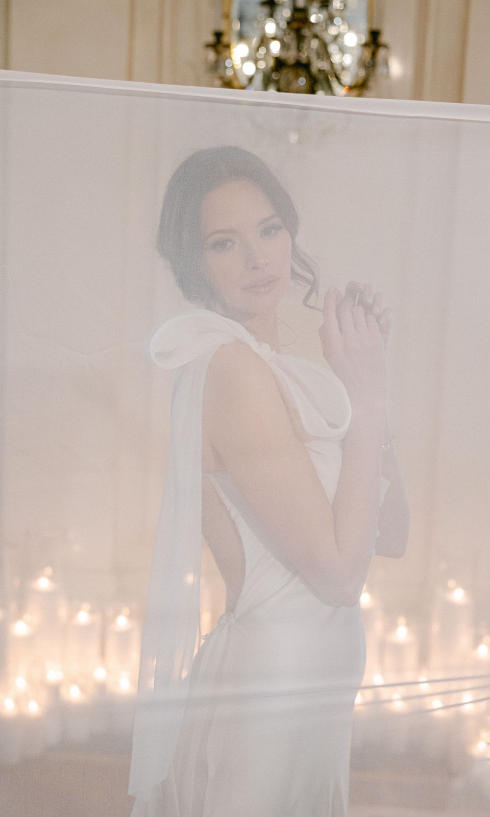 Ethereal bridal portrait with soft lighting and candlelit ambiance in elegant interior.