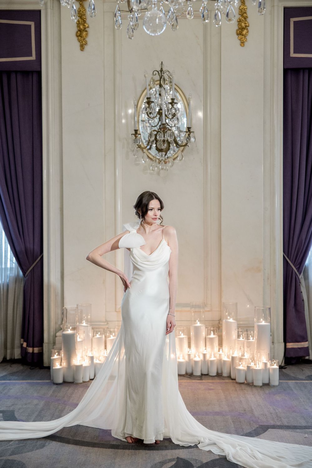Elegant wedding dress showcased in luxurious room with crystal chandeliers and candlelit setting.