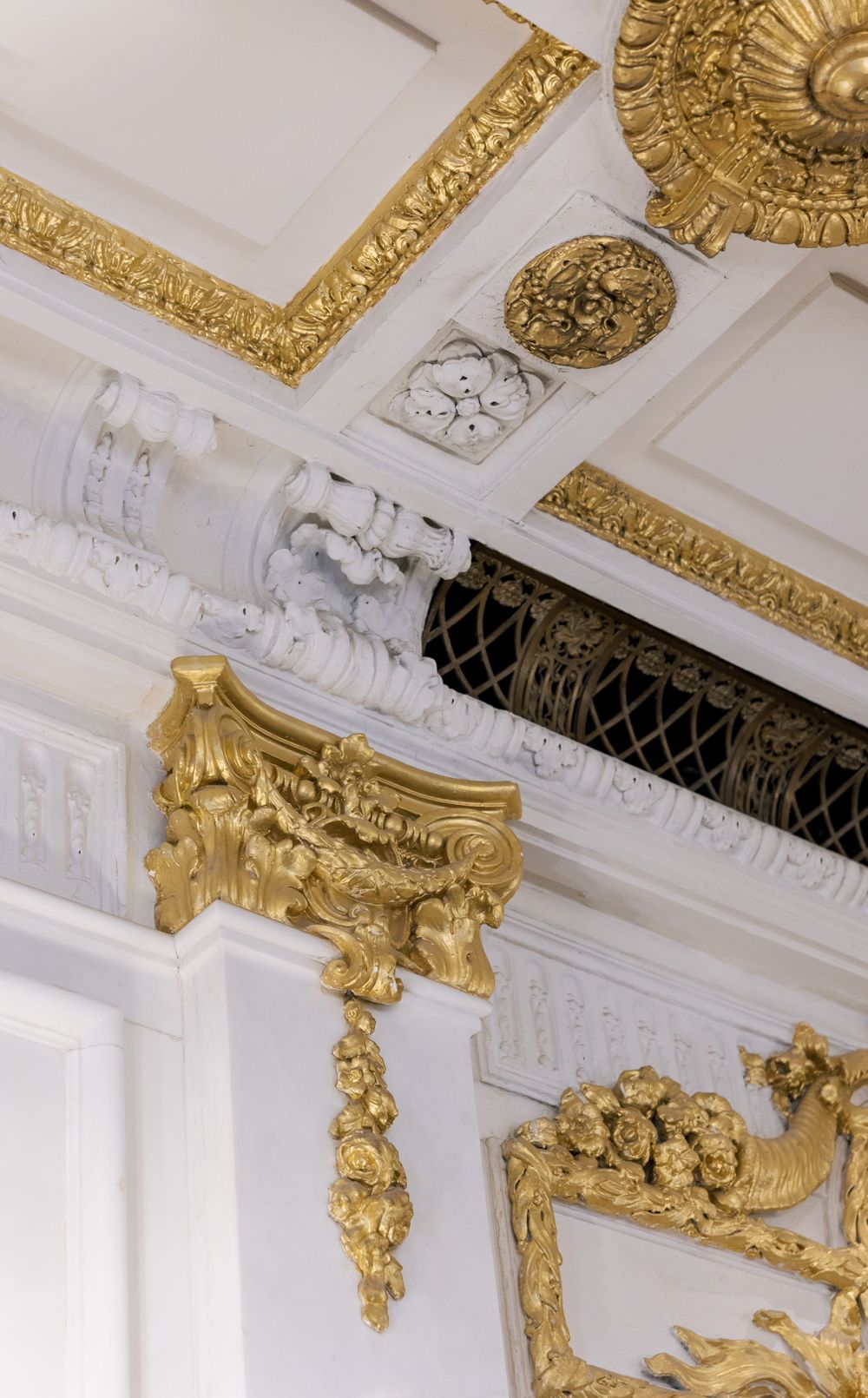 Ornate white and gold baroque architectural details with decorative moldings and gilded accents on a ceiling.