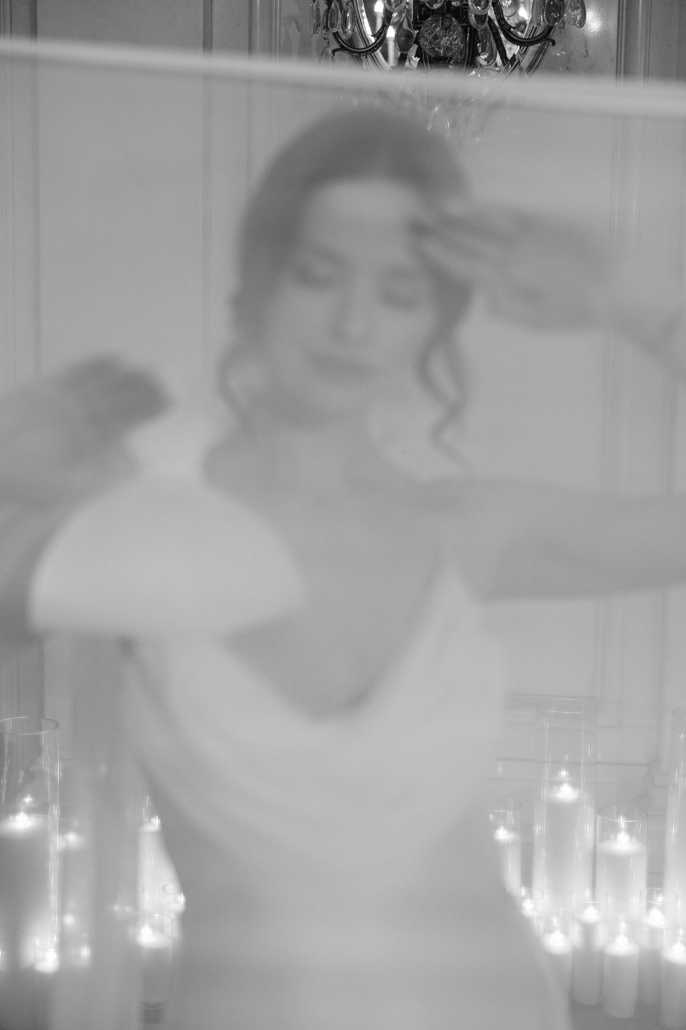 Dreamy soft focus portrait in white bridal gown surrounded by candlelight and crystal fixtures.