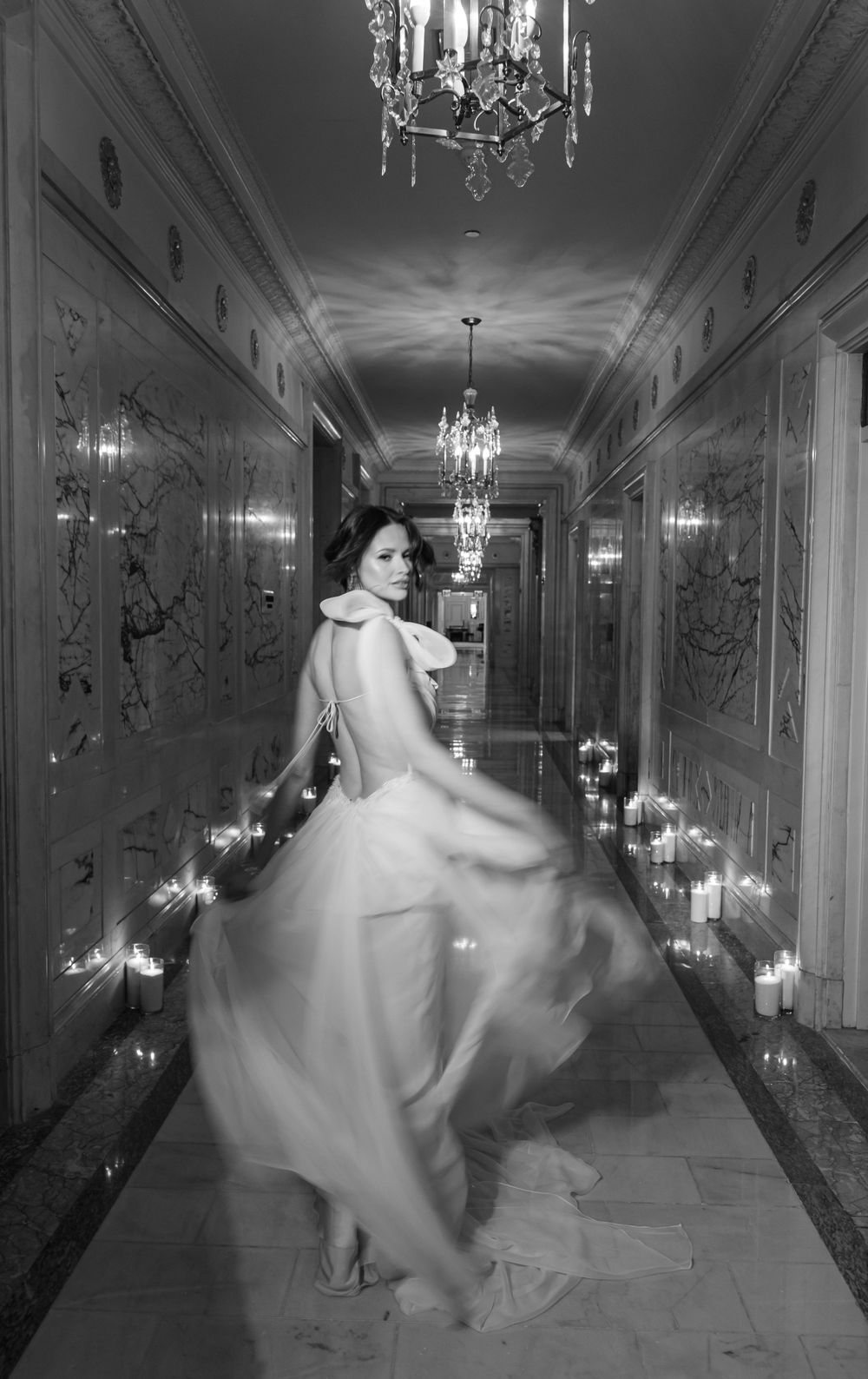 Vintage-style black and white bridal portrait in elegant hallway with flowing dress movement.