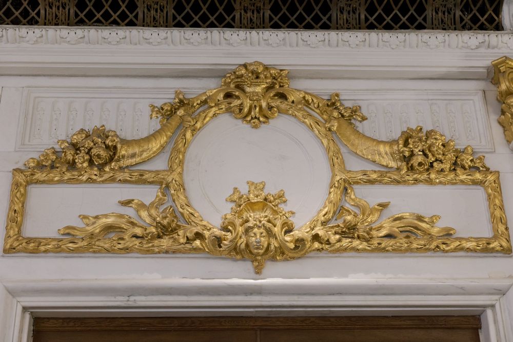 Ornate gold baroque architectural detail with floral motifs on white wall.