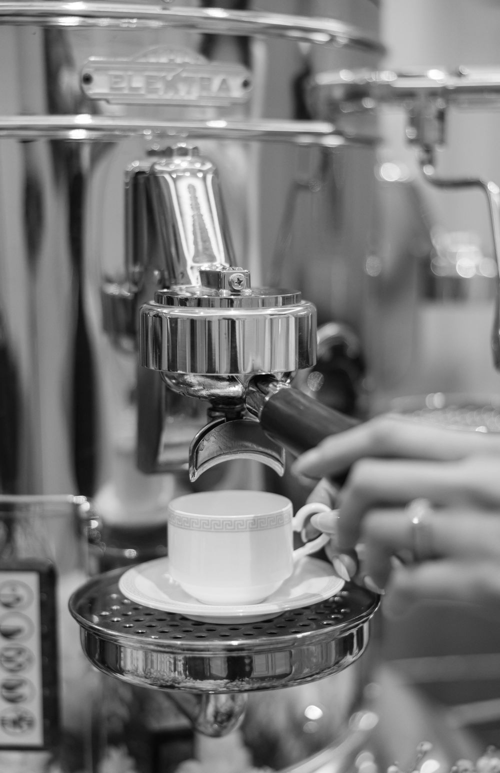 Professional espresso machine brewing coffee into white cup with chrome details.