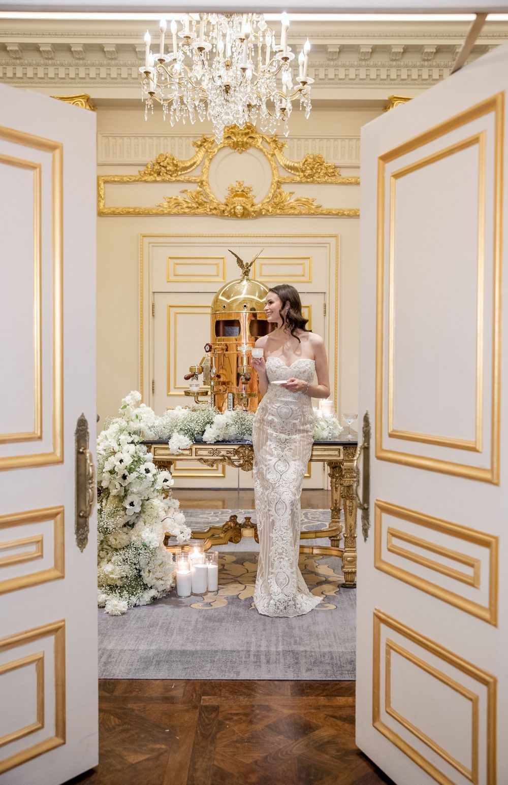 Elegant room with gold trim details and crystal chandelier featuring ornate French doors.