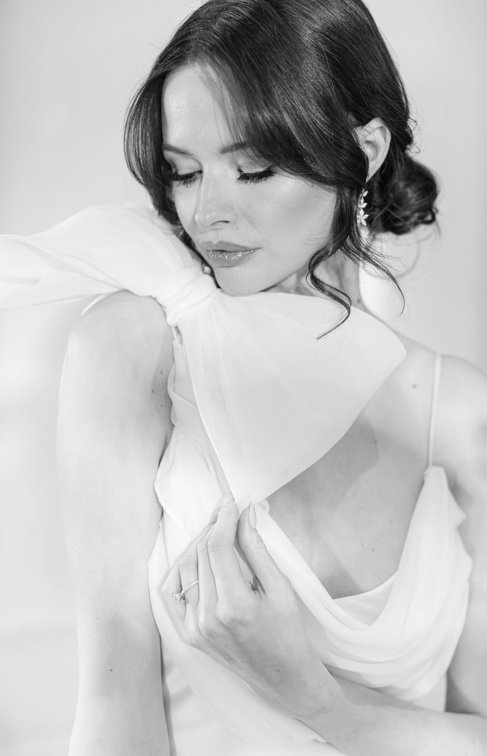 A black and white portrait showing delicate details of a wedding dress and soft styling.
