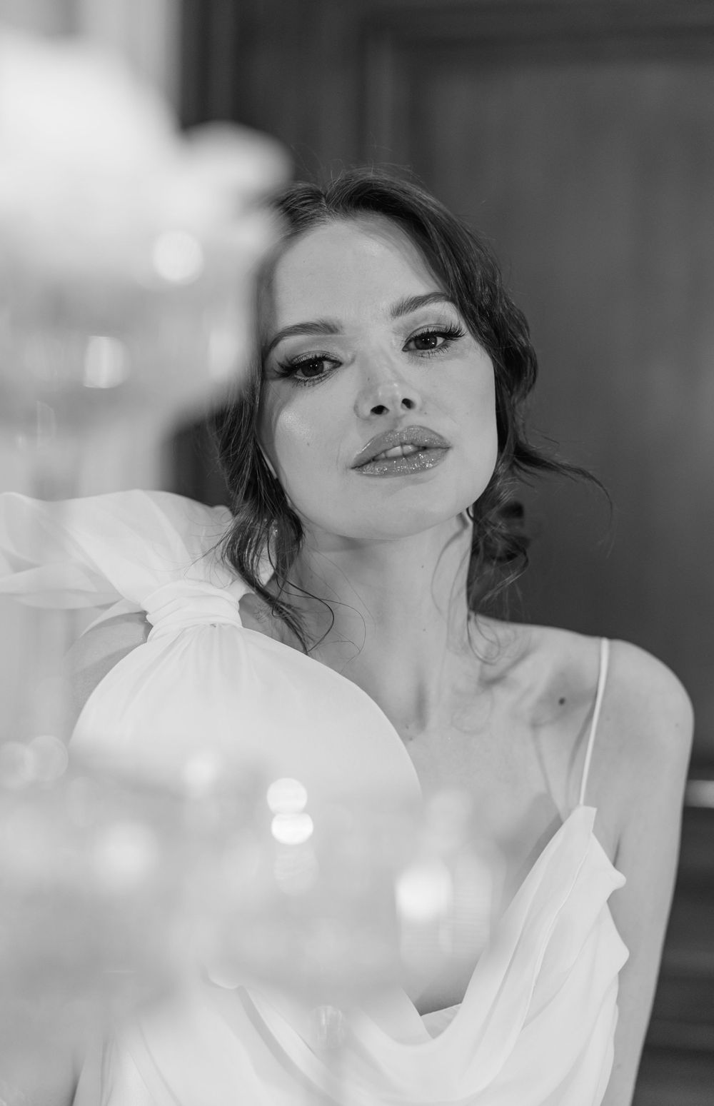 Artistic bridal portrait with soft bokeh lighting effects in elegant indoor setting.