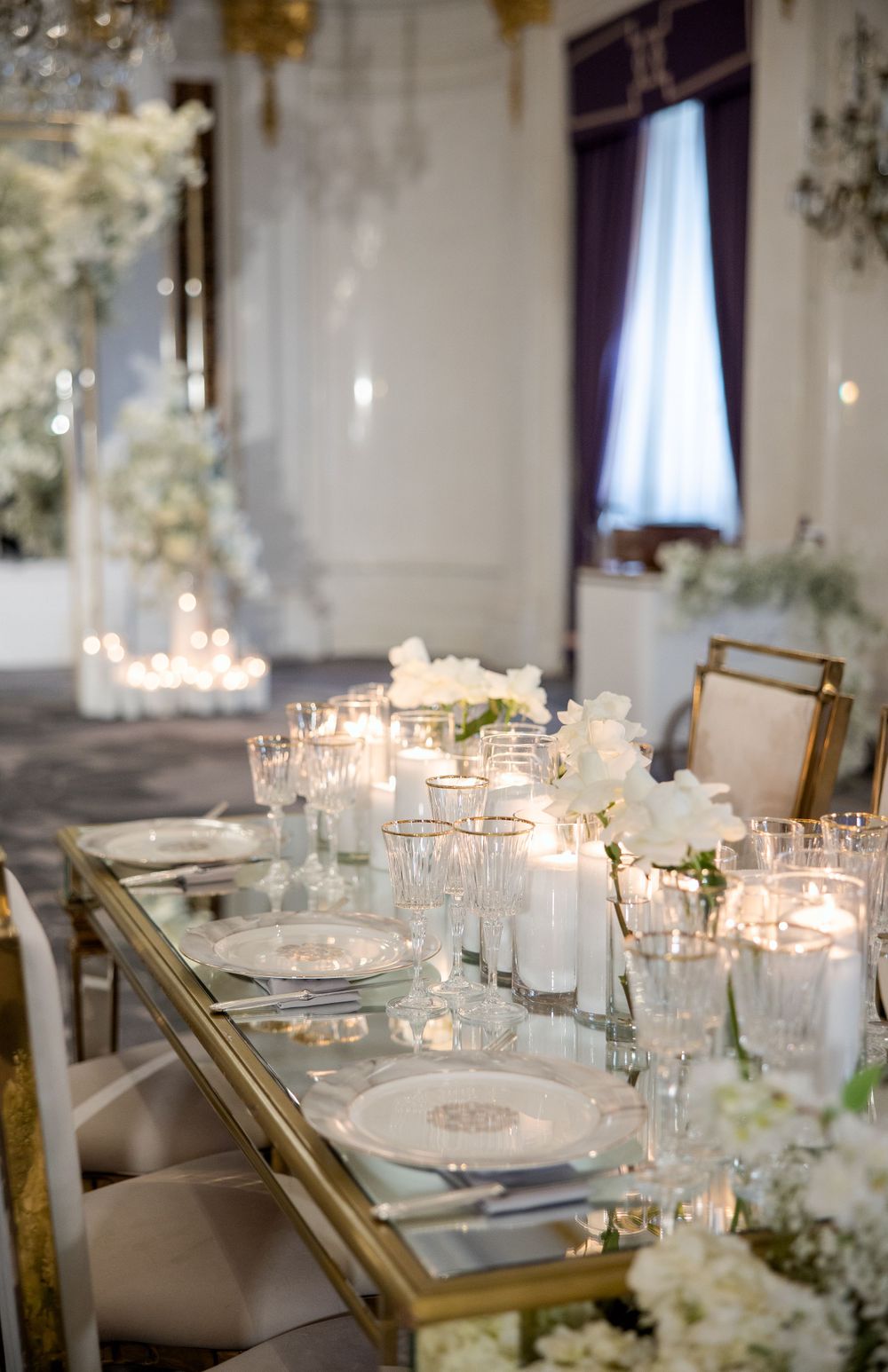 Sophisticated wedding table with gold accents, crystal glassware, and white floral centerpieces.