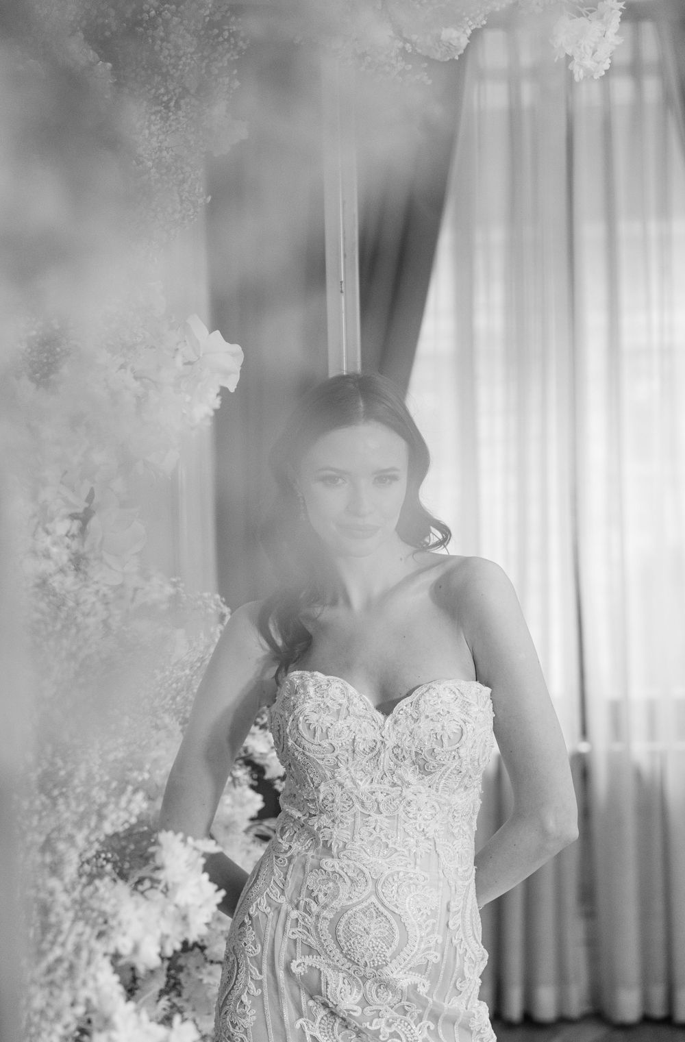 Artistic black and white portrait with soft focus and floral elements.