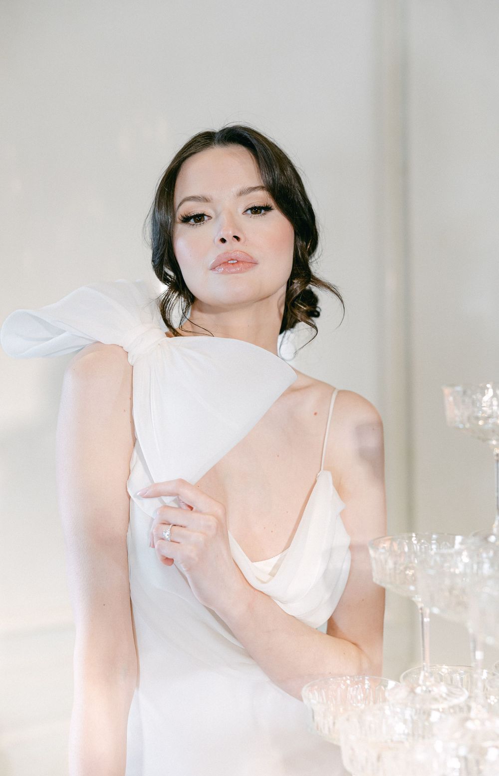 A romantic bridal portrait featuring soft lighting and a champagne tower in an elegant setting.