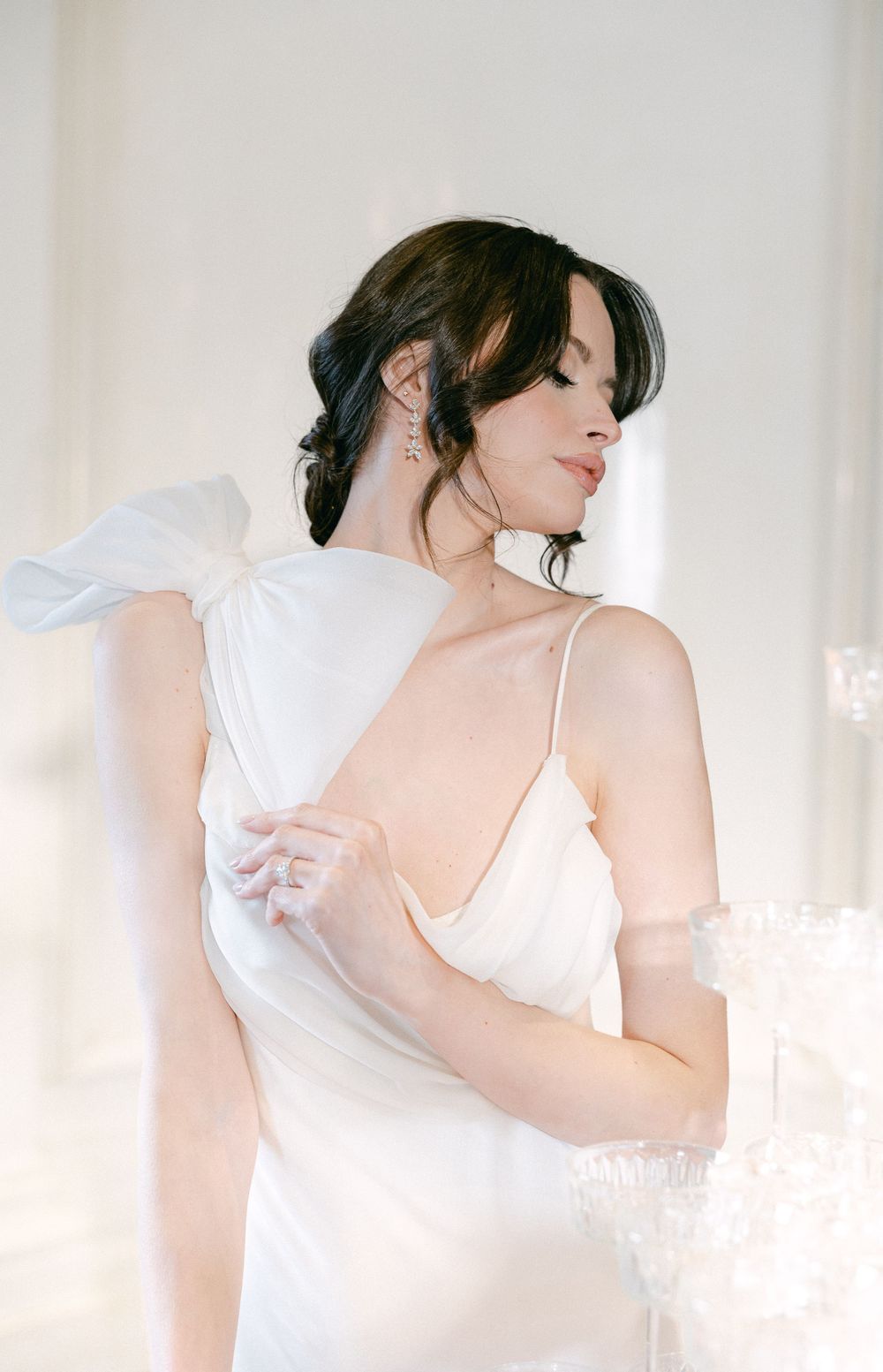 An ethereal bridal portrait with soft lighting and flowing white fabric.