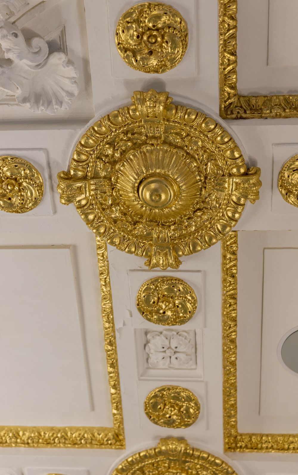 Ornate gold ceiling medallion with intricate baroque details in white and gold.