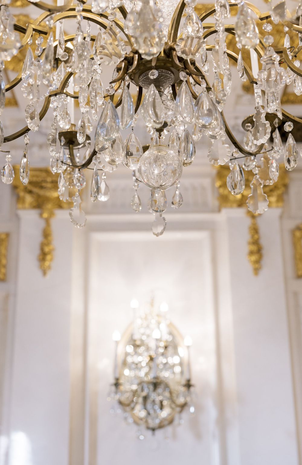 Close-up of crystal chandelier droplets with gold accents against white walls.