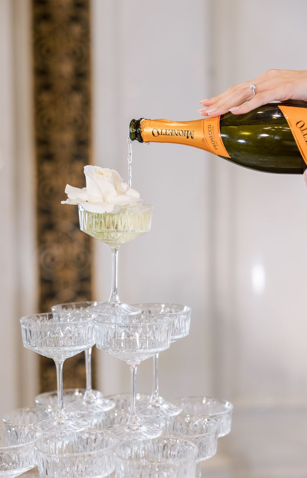 Champagne being poured into a tower of vintage crystal coupe glasses.