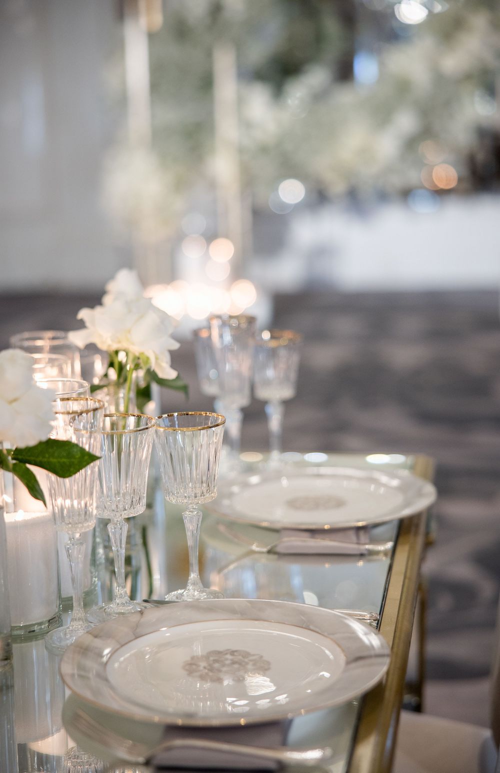 Elegant wedding table setting with crystal glasses, white plates, and soft candlelight creating a romantic atmosphere.