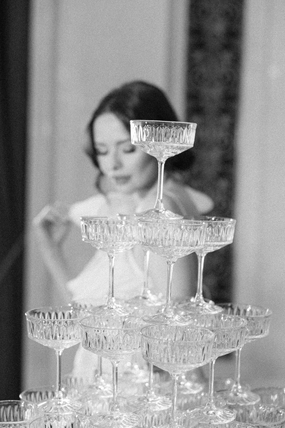 Black and white photo of crystal champagne tower with elegant coupe glasses.