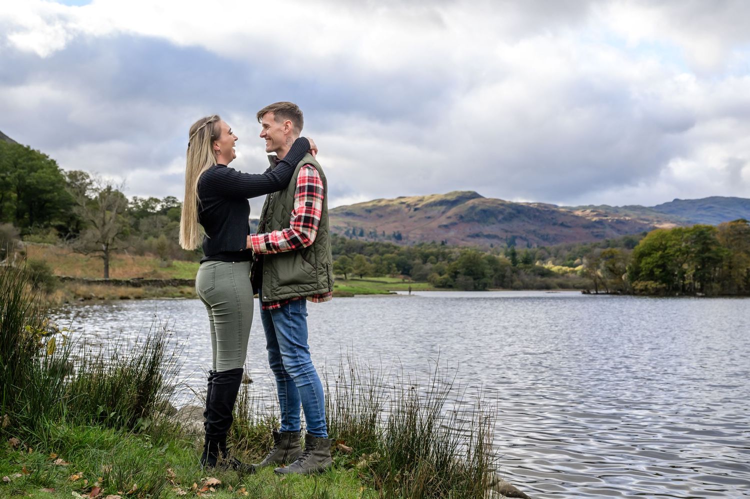 Engaged couple standing beside Rydal Water in Cumbria