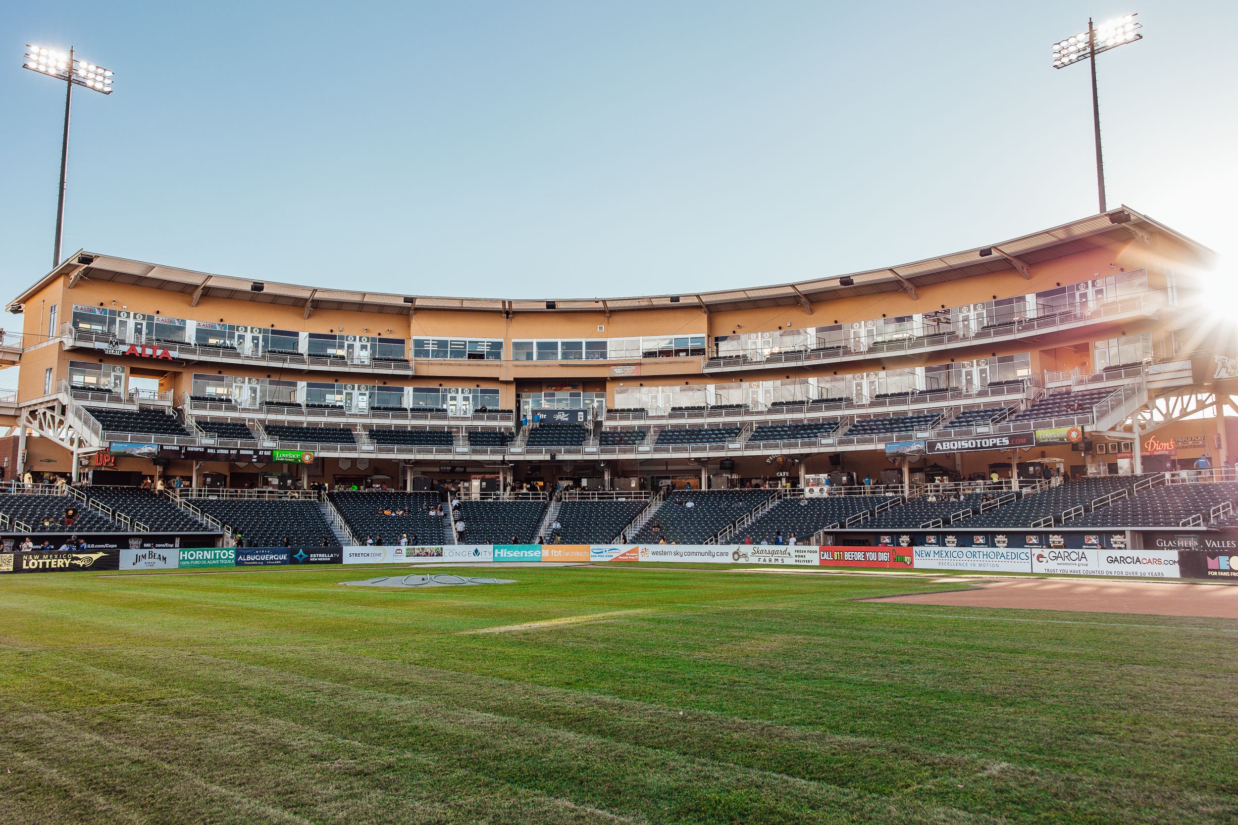 Baseball stadium with curved grandstand seating glows during sunset.