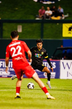 Soccer players from opposing teams compete for ball control during night match.