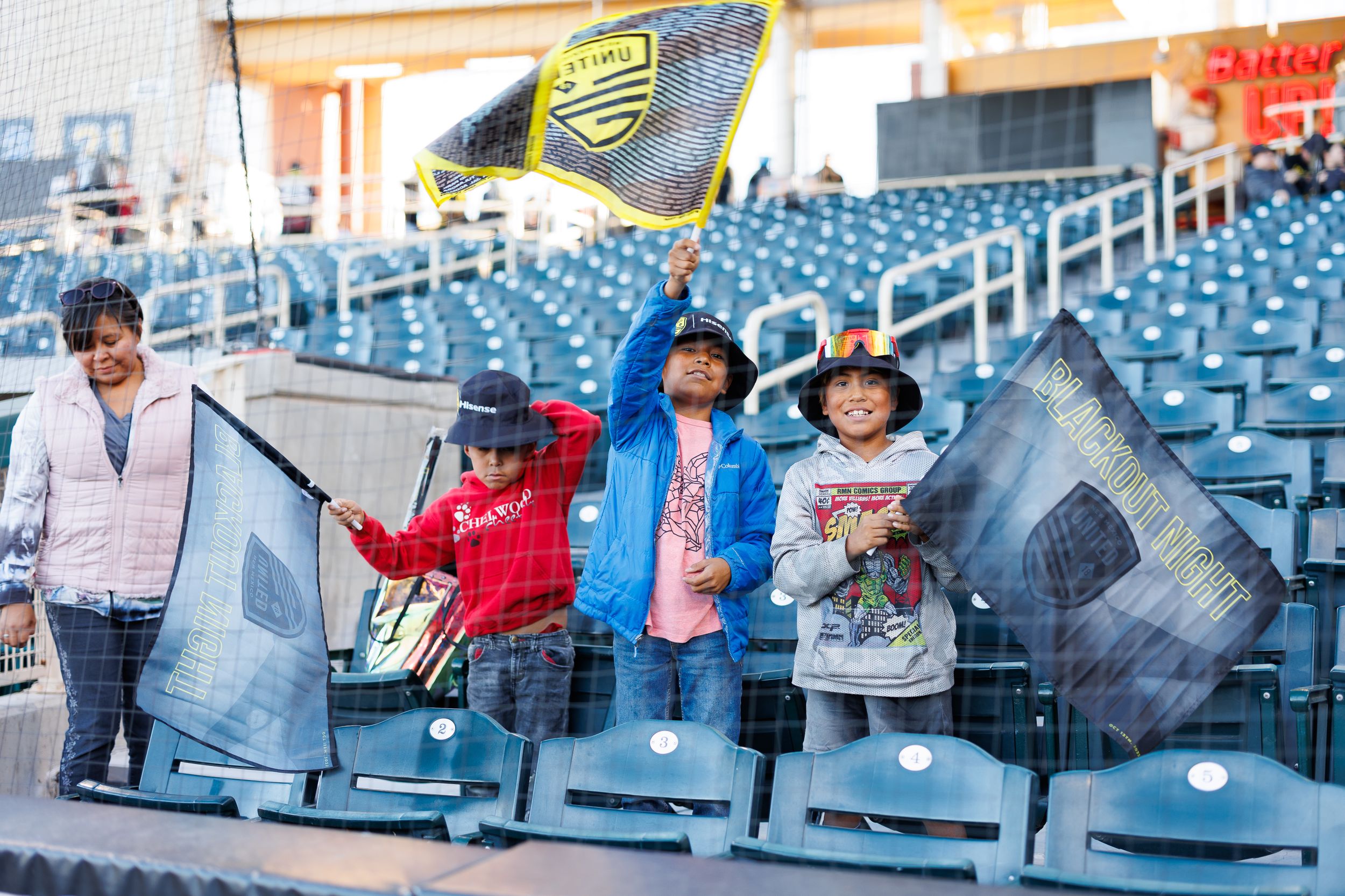 Soccer fans wave flags in stadium seats during match.