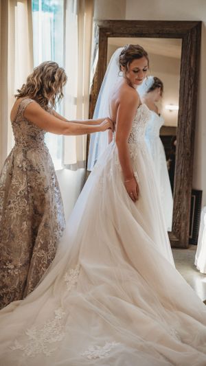 Wedding dress preparation with intricate lace details and flowing train.