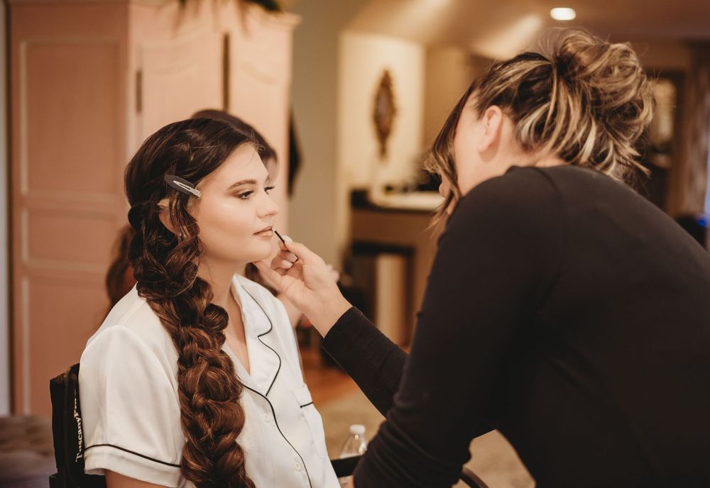 Getting ready scene with makeup application in warm lighting.
