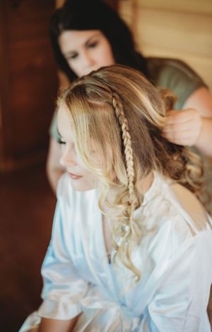 Getting ready scene with elegant hairstyling in white satin robe.