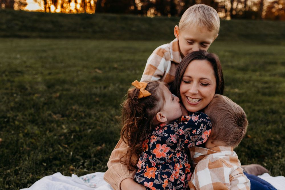 Joyful outdoor family moment captured during golden hour in grassy field.