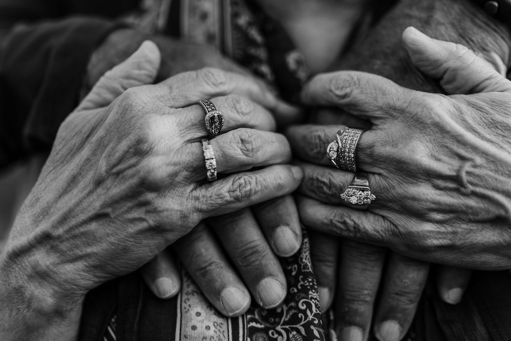 Close up of hands with rings stacked together in black and white photography.