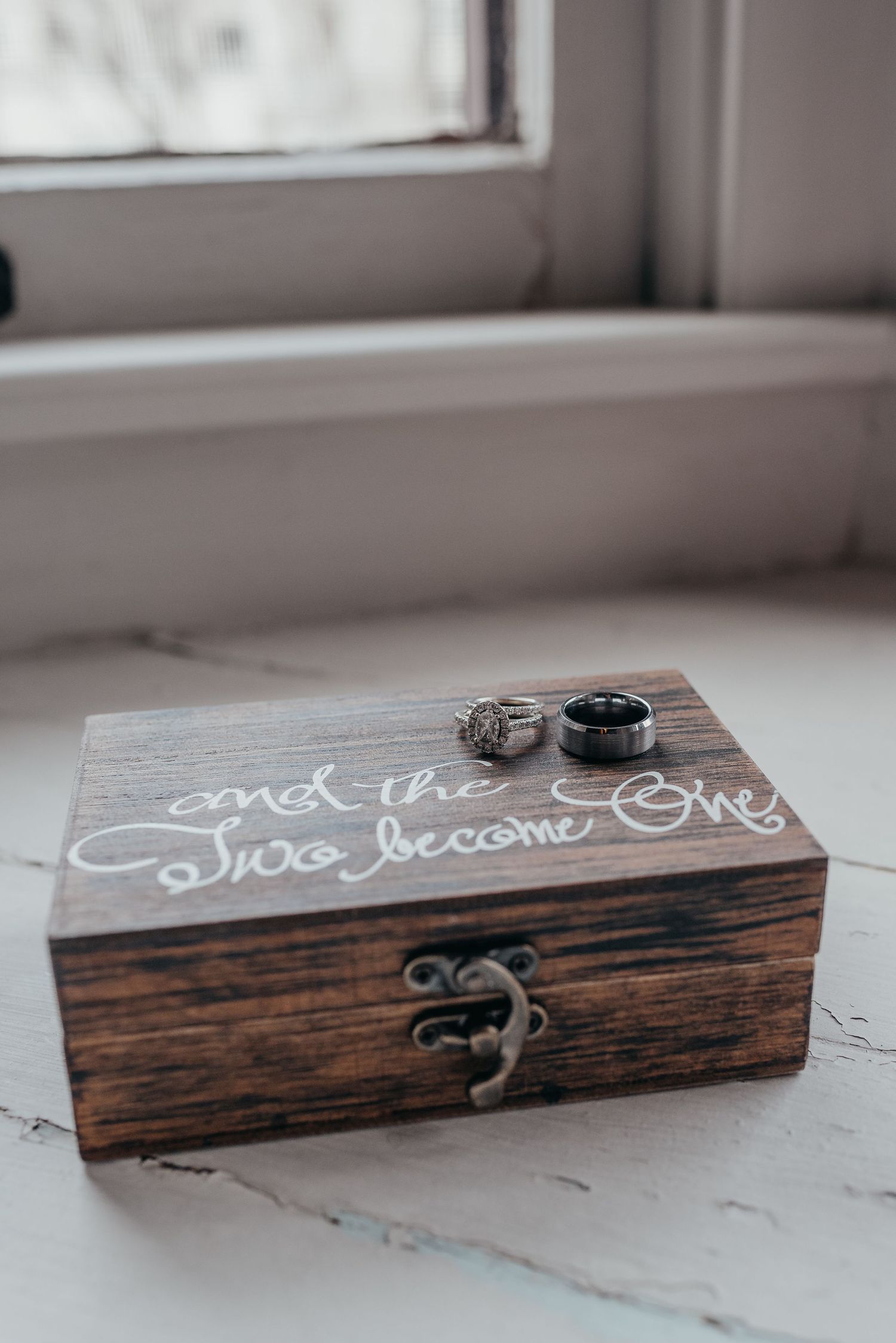 Rustic wooden ring box with handwritten text displayed on white surface.