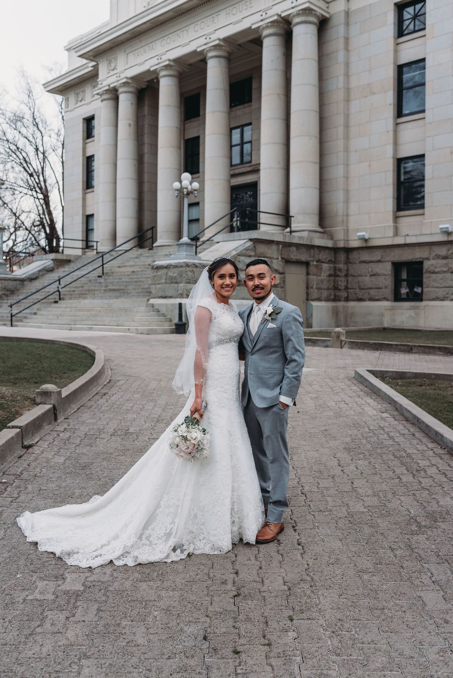 Wedding couple posing in front of grand neoclassical building with columns.