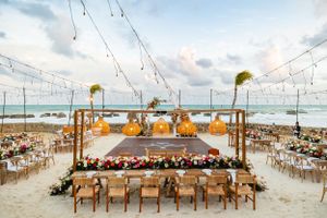 Elegant beach wedding venue with string lights and wooden tables arranged around a central dance floor.