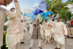 Festive celebration with blue smoke bombs and traditional Indian formal wear.
