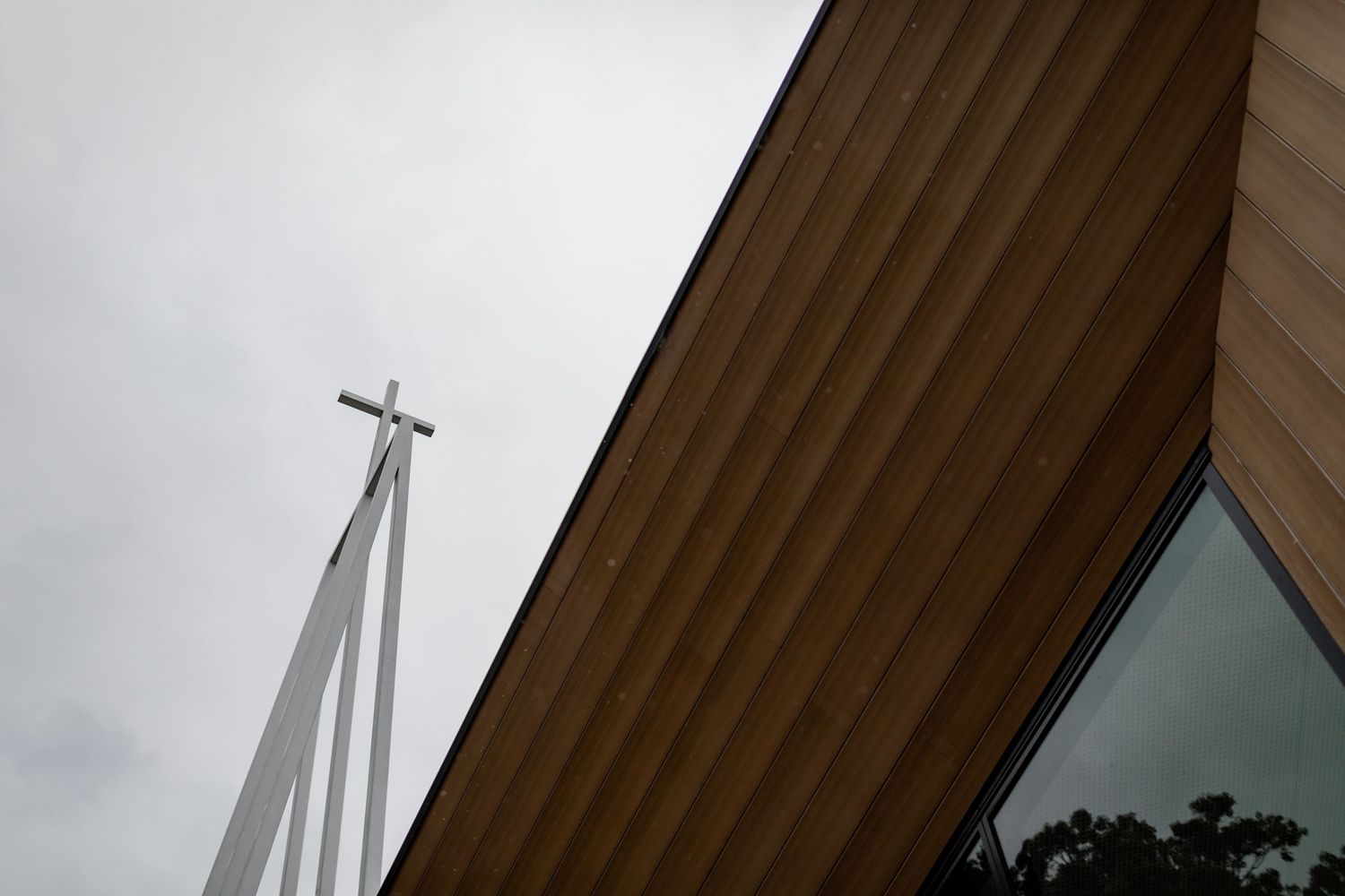 White church steeple cross against overcast sky with wooden architectural details.