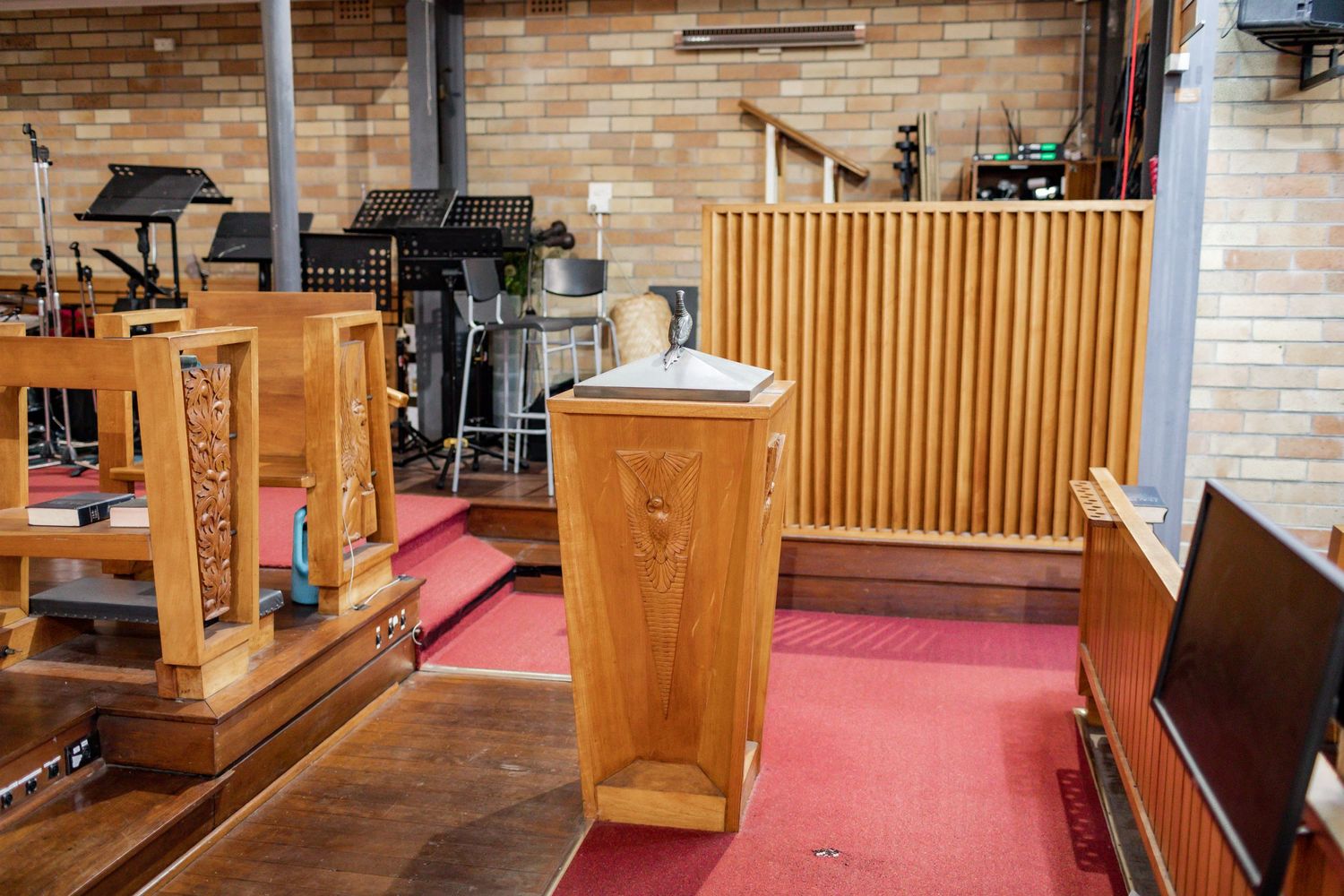 Church pulpit and wooden furnishings on red carpeted platform in sanctuary.
