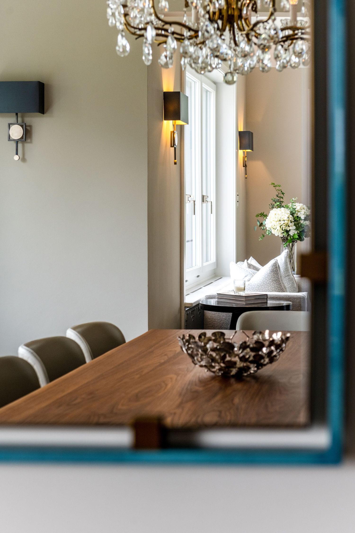 A view through a mirror of a dining table and a seating area beyond.