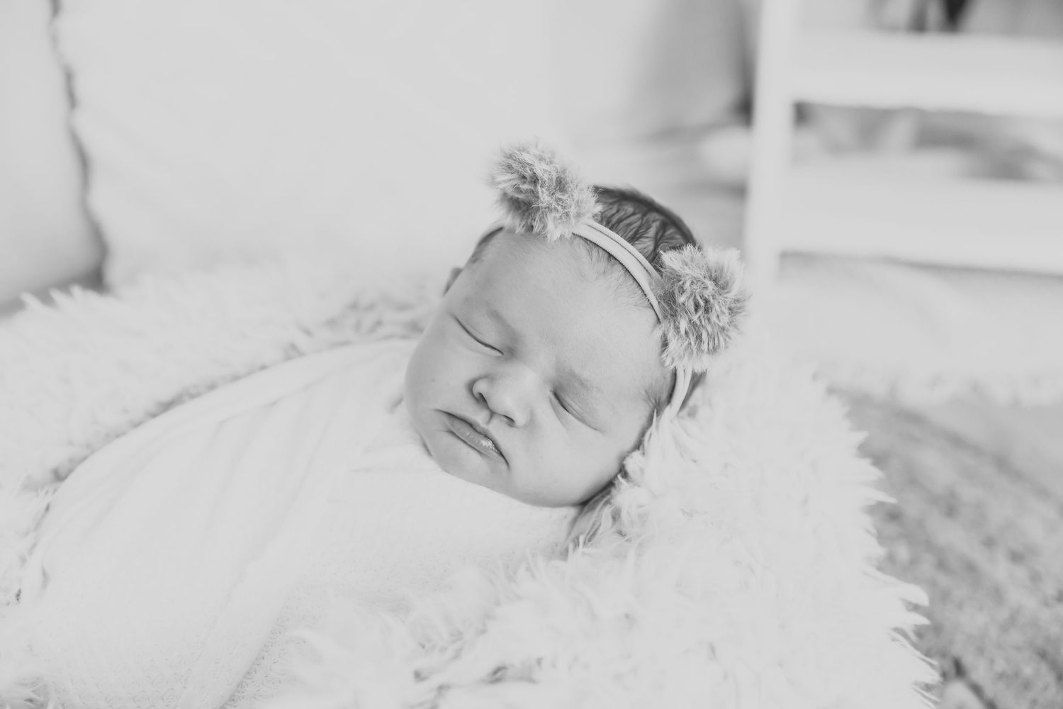 Black and white portrait of sleeping newborn wearing delicate floral crown.