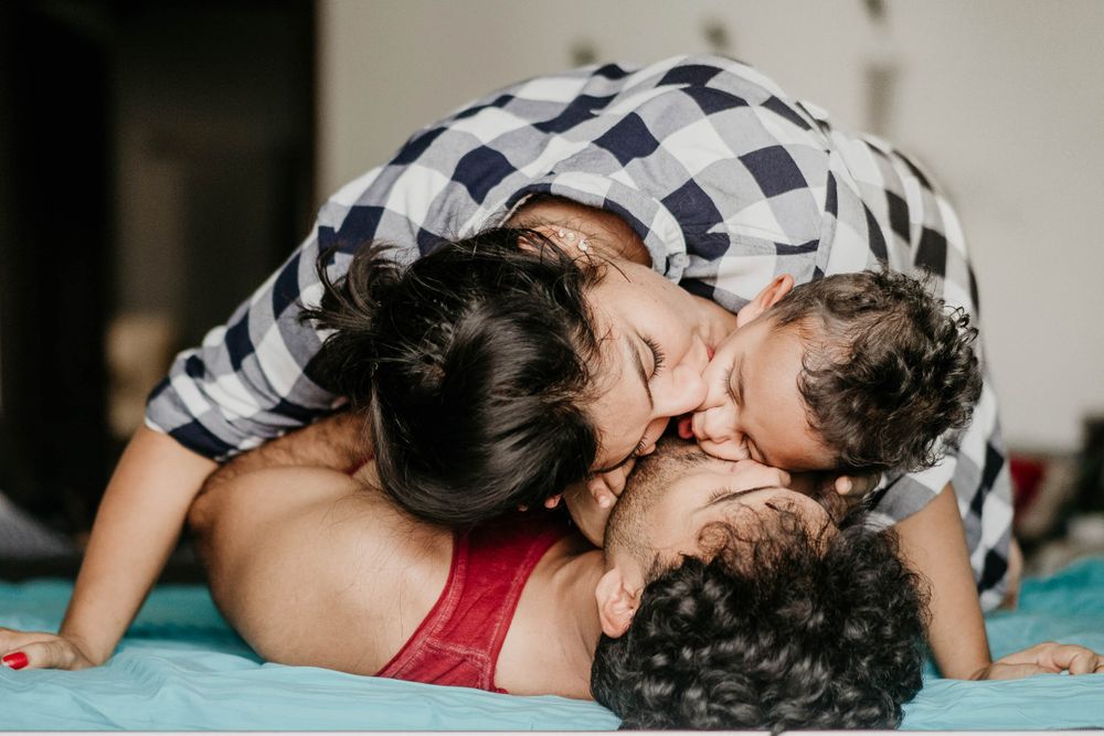 Couple kissing their one year old boy as a part of family portrait session by little vows