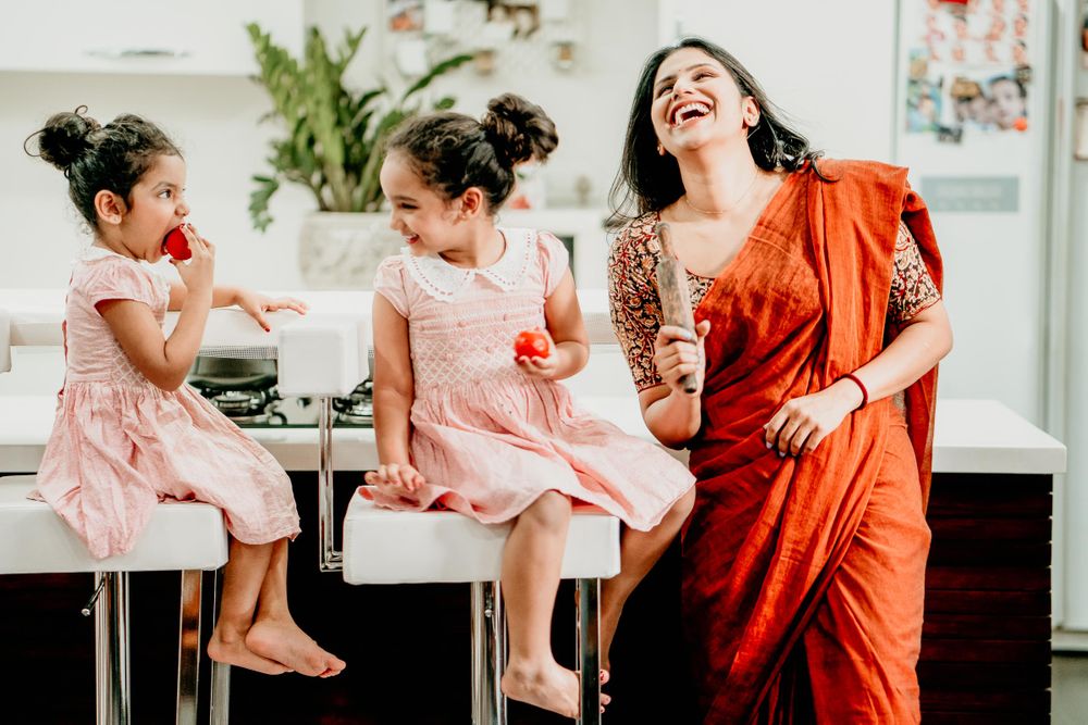 One of a beautiful poses for twin baby girls shoot, posing with their mom in kitchen holding kitchen utensils