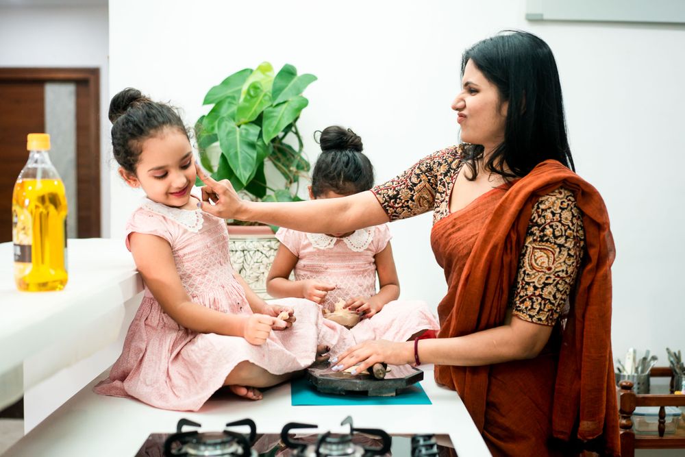 Twin baby girls playing with flour in the kitchen with their mom in hyderabad