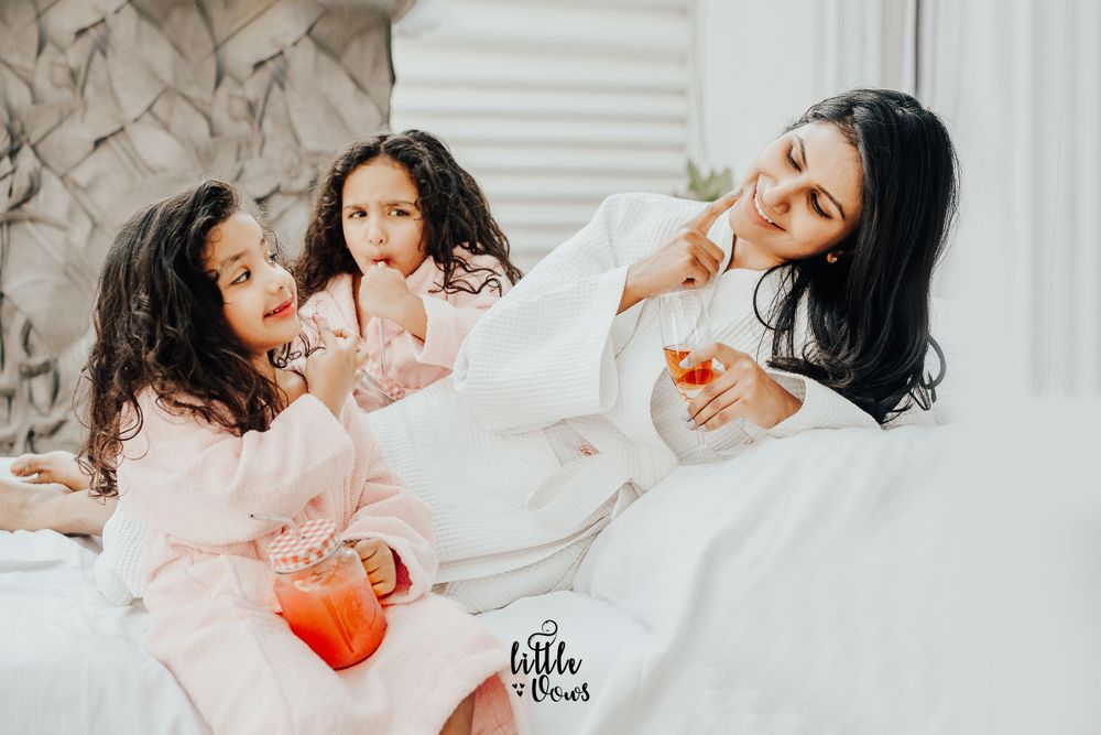 Candid shots by luxury kids photographer, of twin baby girls playing with their mom in bathrobe with juice mugs