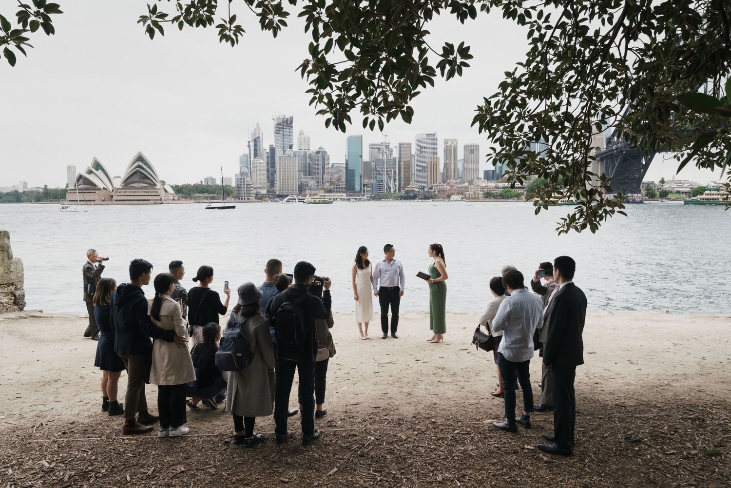 Intimate outdoor wedding ceremony on Sydney Harbour foreshore with city skyline backdrop.