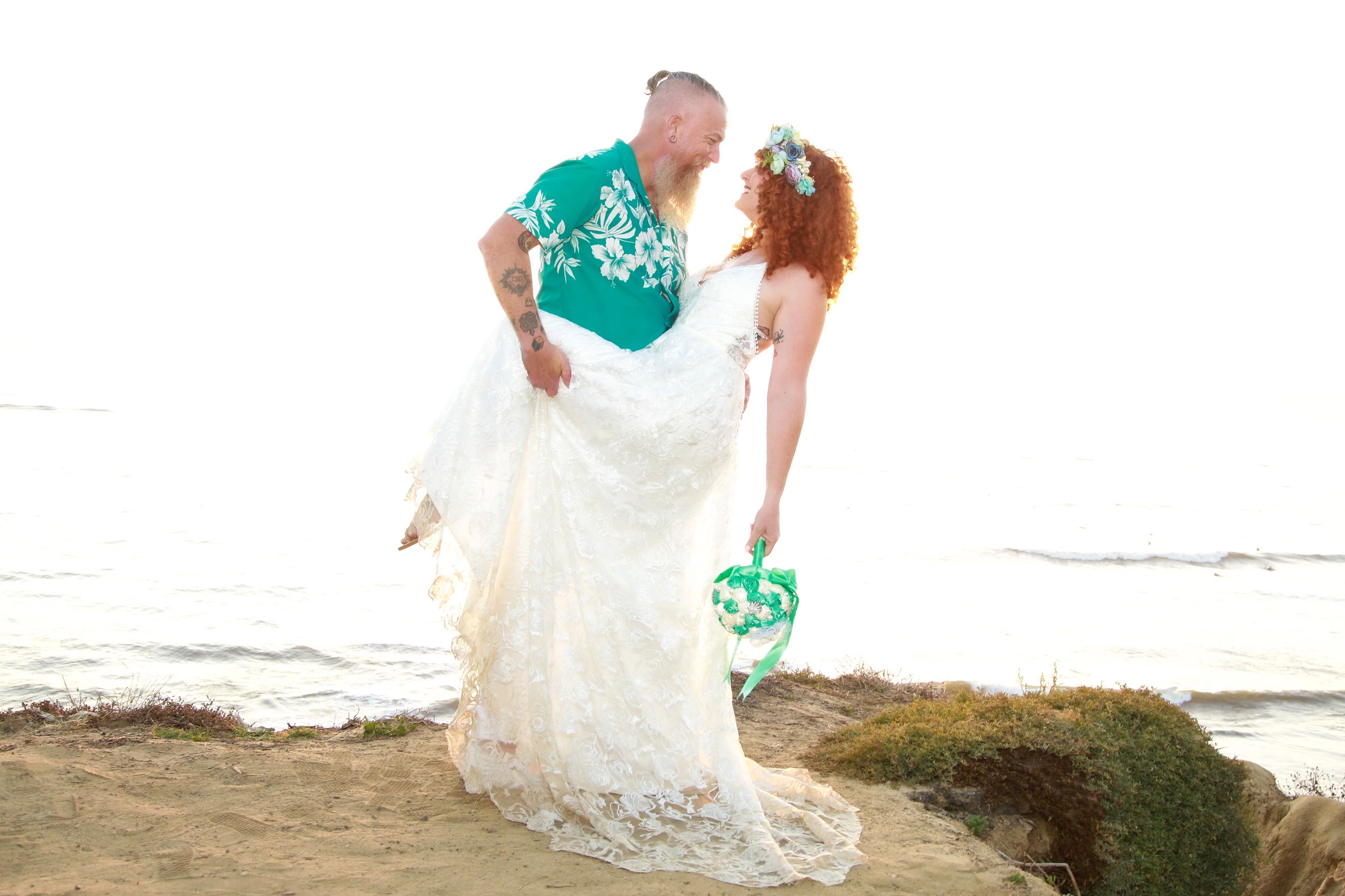 A romantic beach wedding photo showing a couple in turquoise and white against an ocean backdrop.