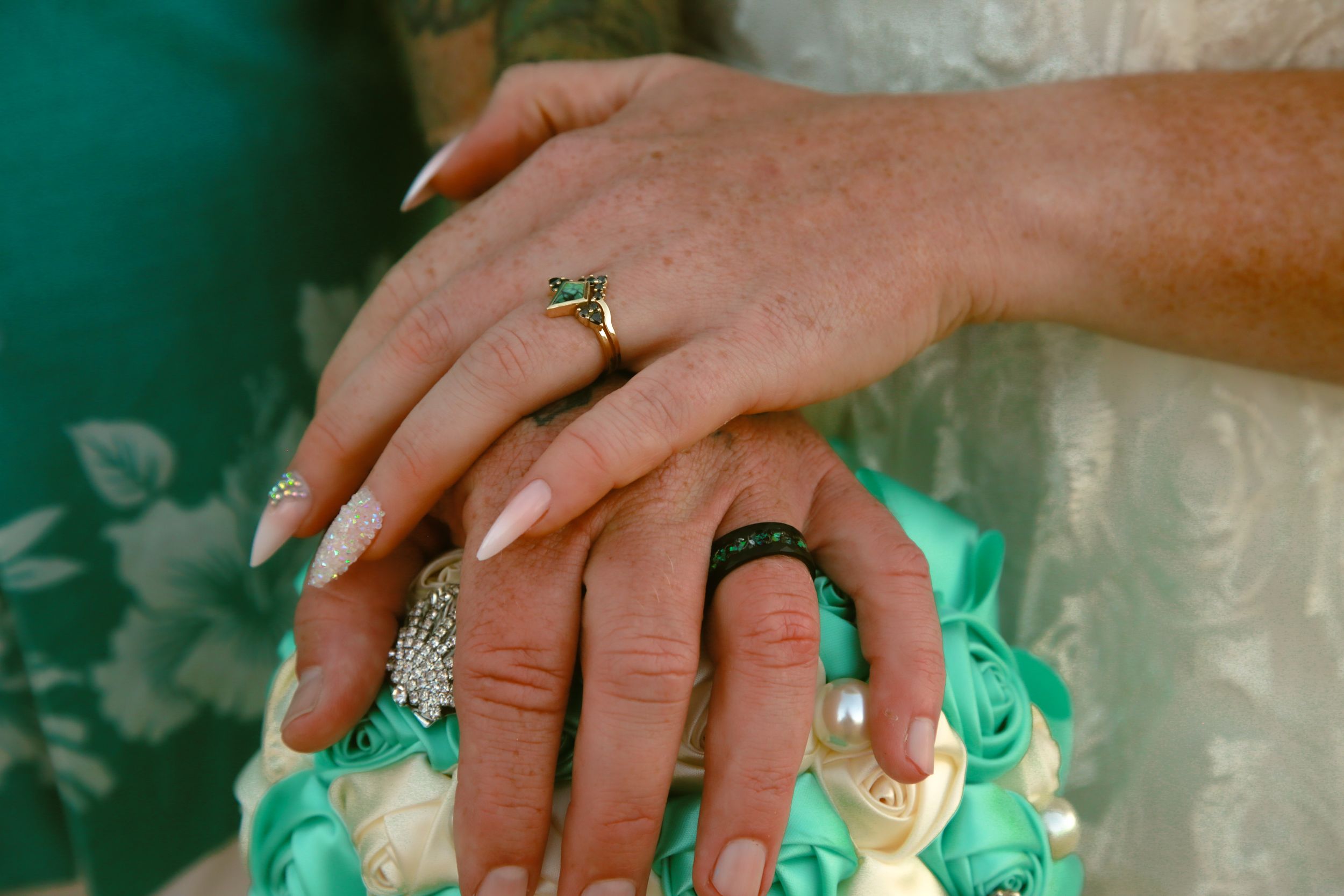 Close-up of hands showing wedding rings with turquoise decorative elements.