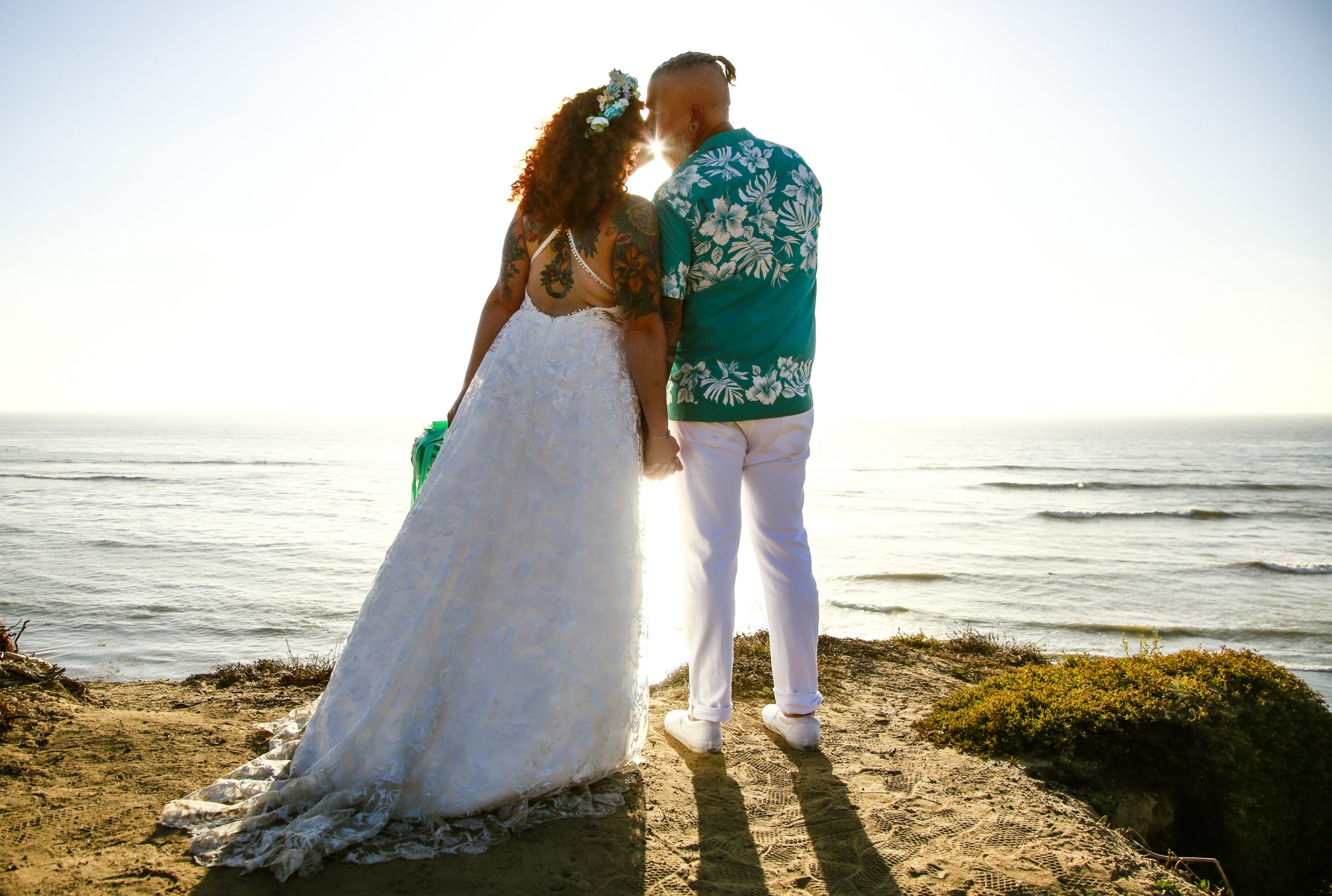 Wedding couple silhouetted against a bright coastal landscape.