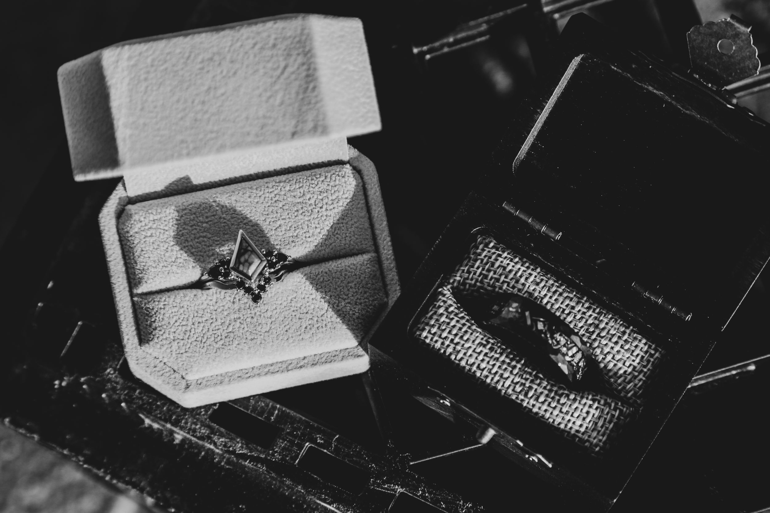 Wedding details including rings and jewelry arranged on a dark surface.