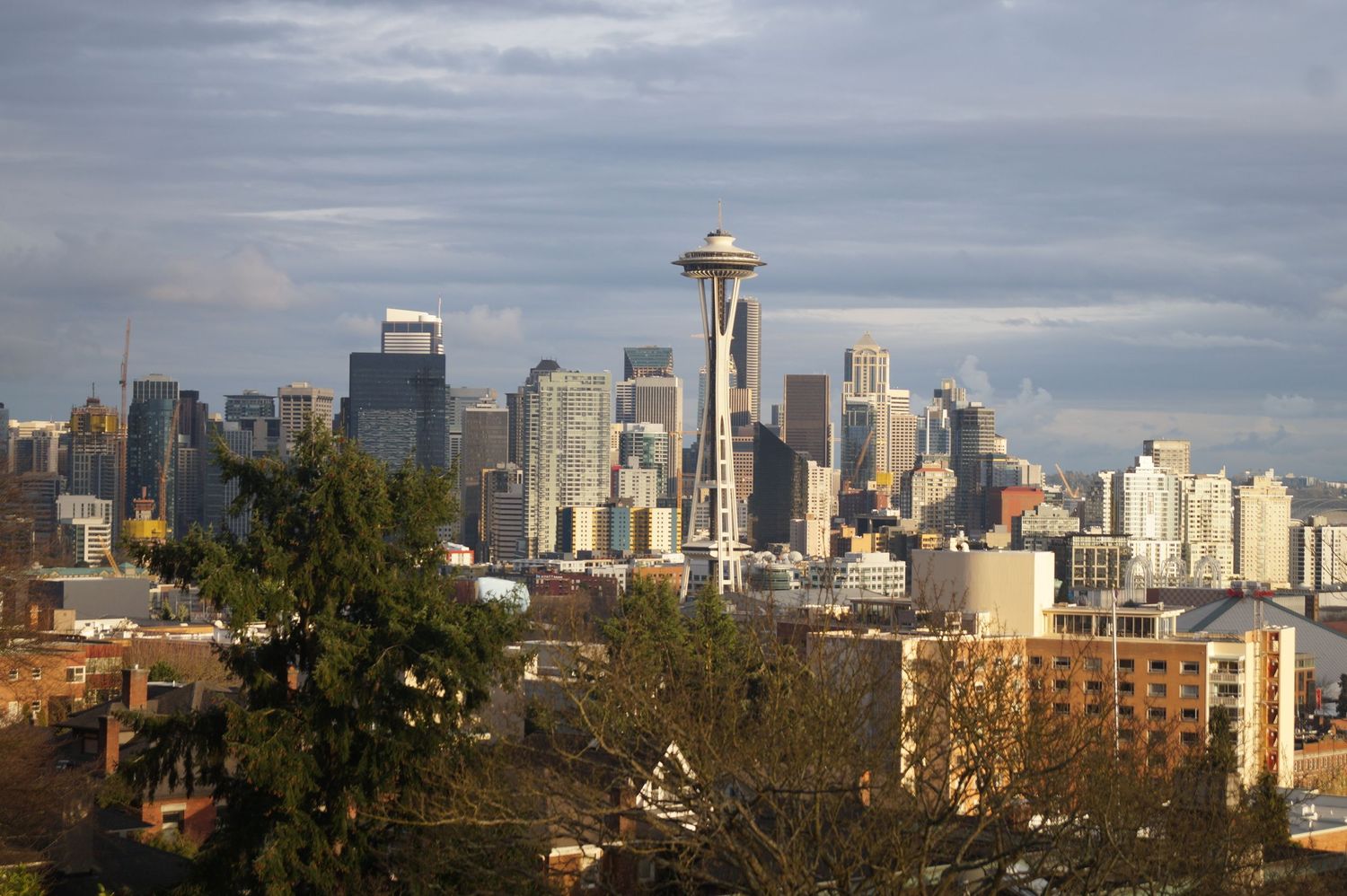 Seattle skyline panorama featuring modern buildings and the Space Needle against cloudy skies.