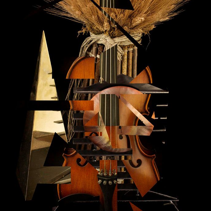 A vintage violin decorated with dried wheat stalks against a black background.