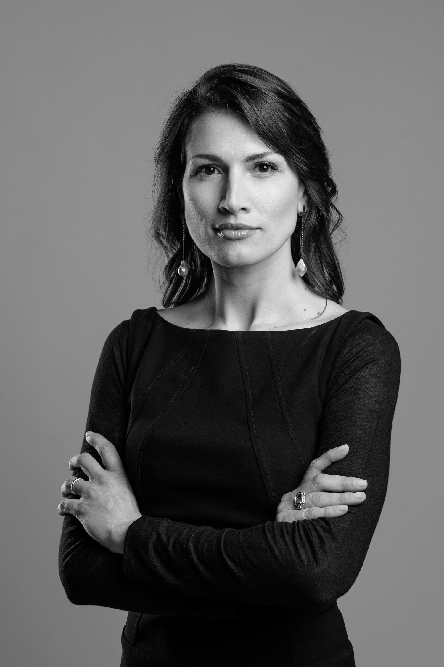 Professional studio portrait in black and white featuring elegant attire and crossed arms pose.