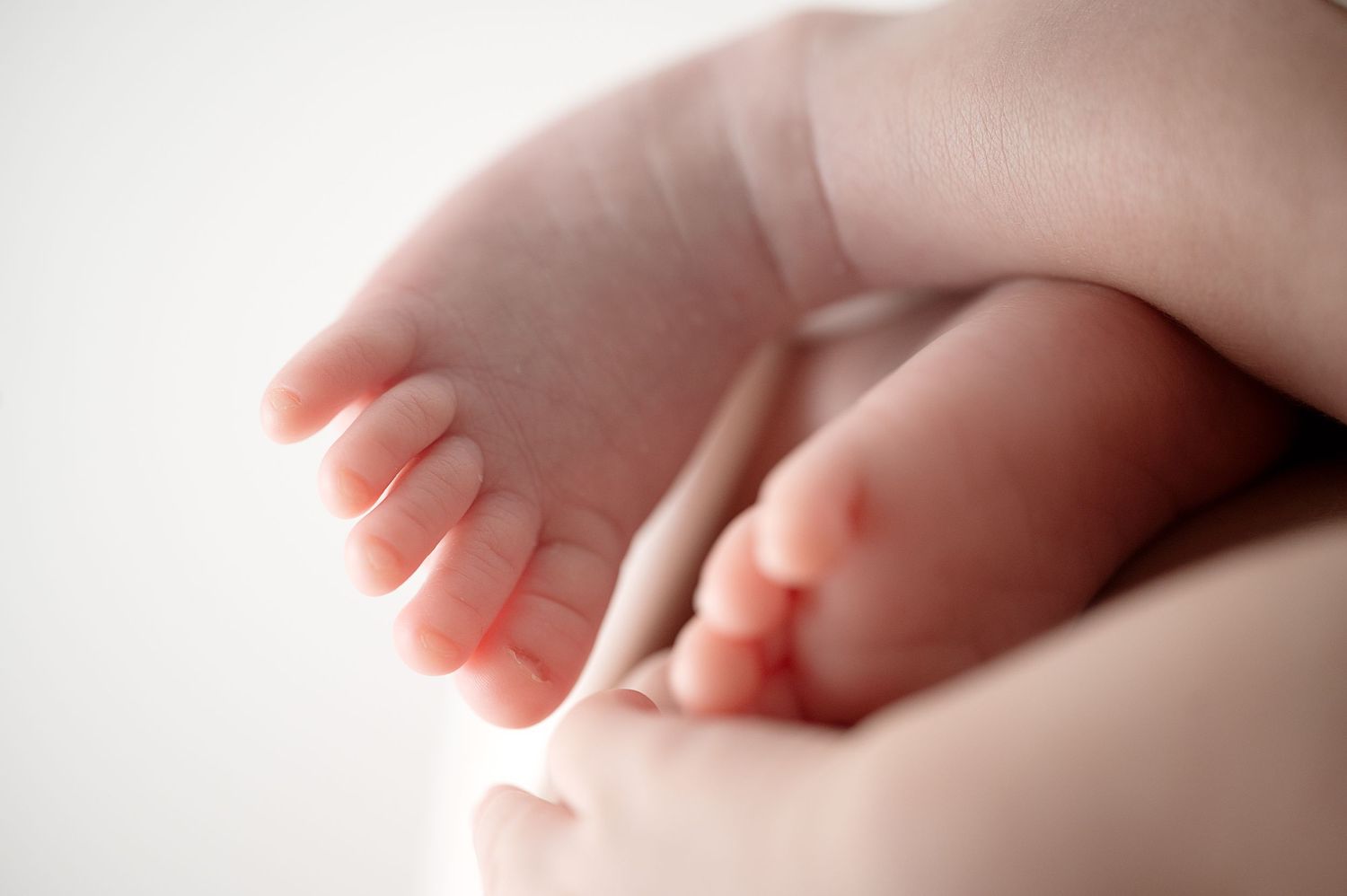 Close-up of tiny newborn baby feet against soft white background.
