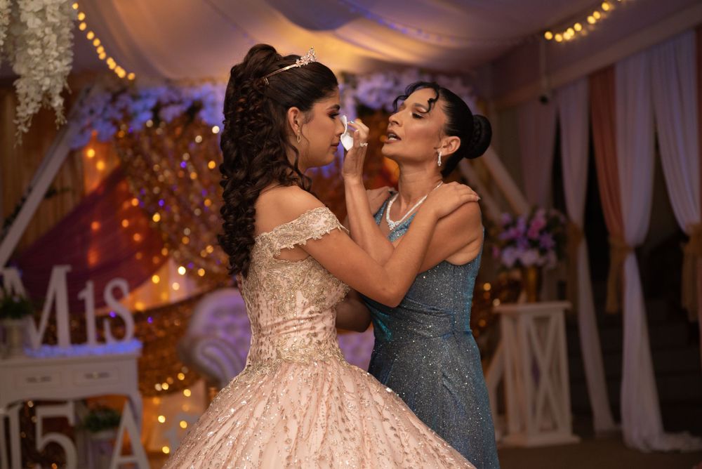 Two people share an intimate dance moment in a beautifully decorated reception hall with twinkling lights.